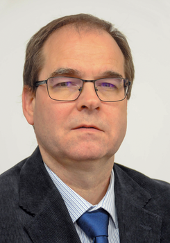 Férfi öltönyben és nyakkendővel Egy férfi öltönyt és kék nyakkendőt visel, fehér csíkos inggel.
