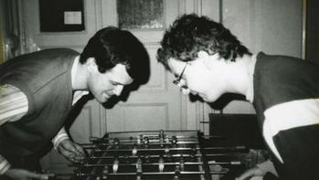 Két ember asztali focit játszik beltérben Két ember asztali focit játszik egy beltéri helyiségben, koncentrálva a játékra.