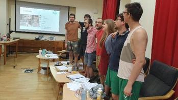 Csoportos prezentáció egy teremben Csoport ember egy teremben, háttérben kivetítőn diavetítés látható.
