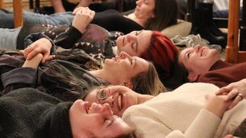 Több ember fekszik a földön, valószínűleg csoportos relaxációs vagy meditációs gyakorlat részeként.