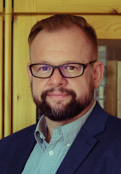 Elegáns férfi fa szekrény háttérben Elegáns öltözetű férfi fa szekrények előtt áll