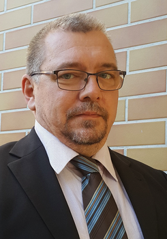 Elegáns férfi öltönyben téglafal előtt Elegáns öltönyös férfi nyakkendővel téglafal előtt