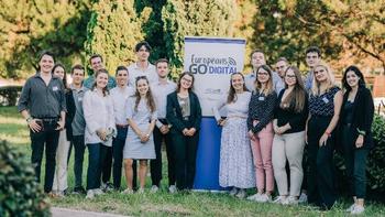 Europeans Go Digital csoportkép egy rendezvényen Fiatalok csoportképe egy 'Europeans Go Digital' feliratú molinó előtt, szabadtéri rendezvényen.