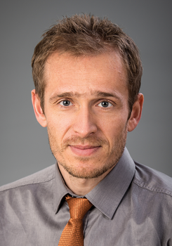 Férfi szürke ingben és narancssárga nyakkendőben Férfi szürke inget és narancssárga nyakkendőt visel, háttér homályos.