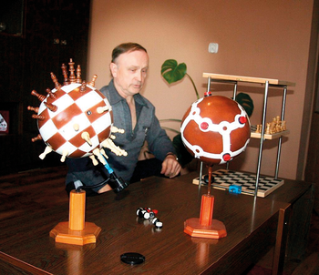 Geometriai és kémiai modellek egy asztalon Geometriai és kémiai modellek, köztük sakktábla mintás gömb és molekulamodellek egy asztalon.