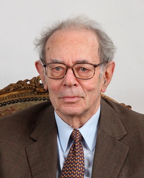 Idős férfi elegáns öltönyben díszes székben Idős férfi elegáns öltönyben és nyakkendőben, díszes székben ülve.