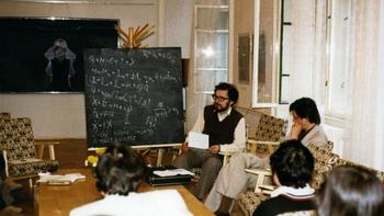Matematikai előadás egy csoport számára Egy férfi matematikai képleteket magyaráz egy csoportnak egy szobában.