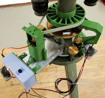 Mechanikus mérőberendezés zöld és fém alkatrészekkel Mechanikus eszköz zöld és fém alkatrészekkel, LED-ekkel és kábelekkel egy állványon.