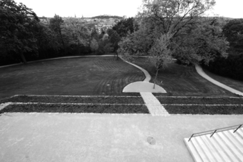 Park sétányokkal és város panorámával Park sétányokkal, fákkal és gondozott gyep, háttérben város panorámája.