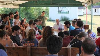 Szabadtéri előadás fiatalokkal Fiatalok csoportja egy szabadtéri előadáson, ahol egy férfi beszél.