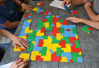 Színes puzzle játék emberekkel egy asztalon Emberek színes puzzle darabokkal játszanak egy asztalon, kreatív szórakozás.